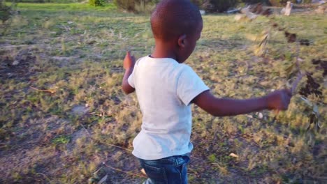 black boy playing with a stick in the grass