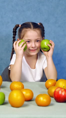 beautiful girl with healthy food. happy little girl sitting on the table with fruits