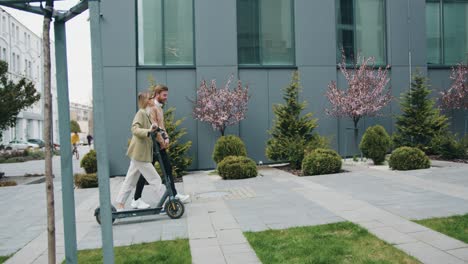 two smiling colleagues going downtown street talking. office managers commuting to work with eco-friendly vehicles. technology, partnership, occupation concept