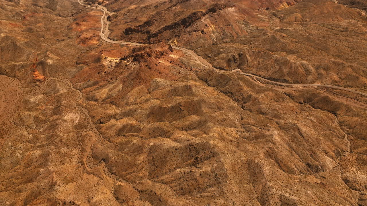 Brown dry landscape of Mojave desert. Rocky landscape with a highway in the middle. Top view.