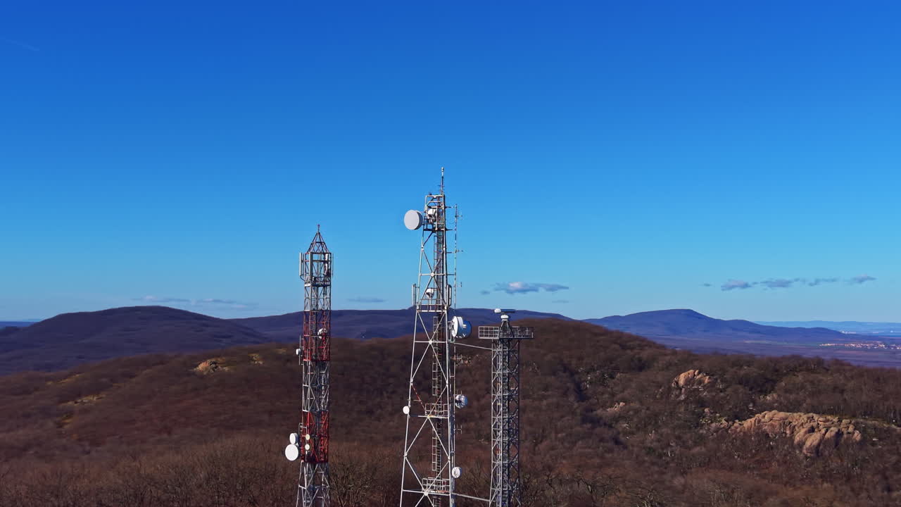 Tower structure on a mountain top with clear blue sky and distant hills in the background during daytime