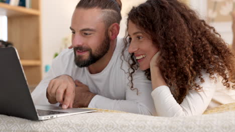 Couple-with-laptop-smile-on-bed