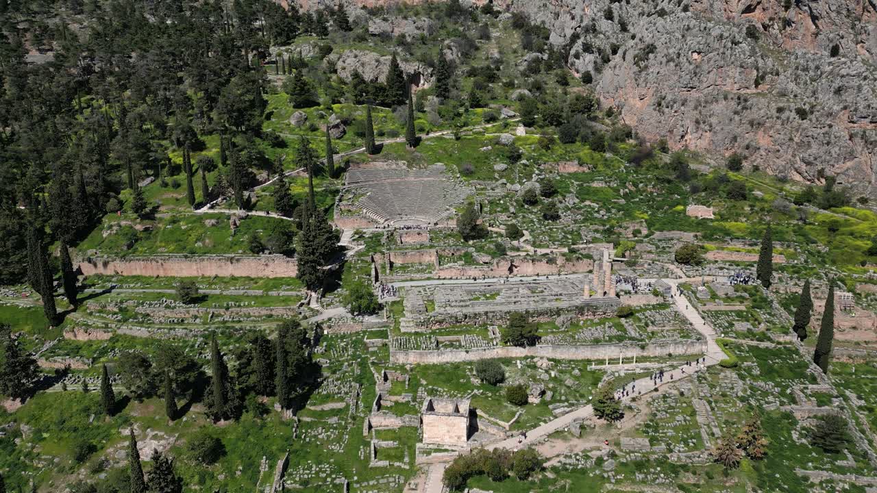 Aerial establishing of ancient Delphi amphitheatre among trees and Greek hills, circular structure