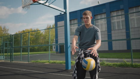 sporty man bouncing volleyball on outdoor court with background of building and greenery, capturing dynamic action, athleticism, and outdoor sports environment