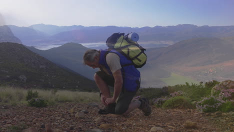 male hiker kneeling tying boot on rocky trail, with animated health tracker overlay