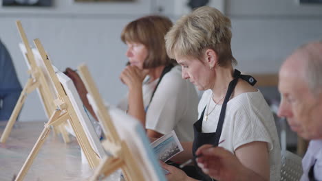 like senior friends attending together at a painting class. small group taking a variety of fun classes together. a group of elderly people attend a master class on drawing together spending time.