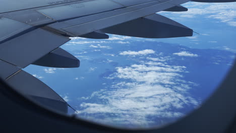 view out of flight passenger window over a sea of cloud and airplane wings