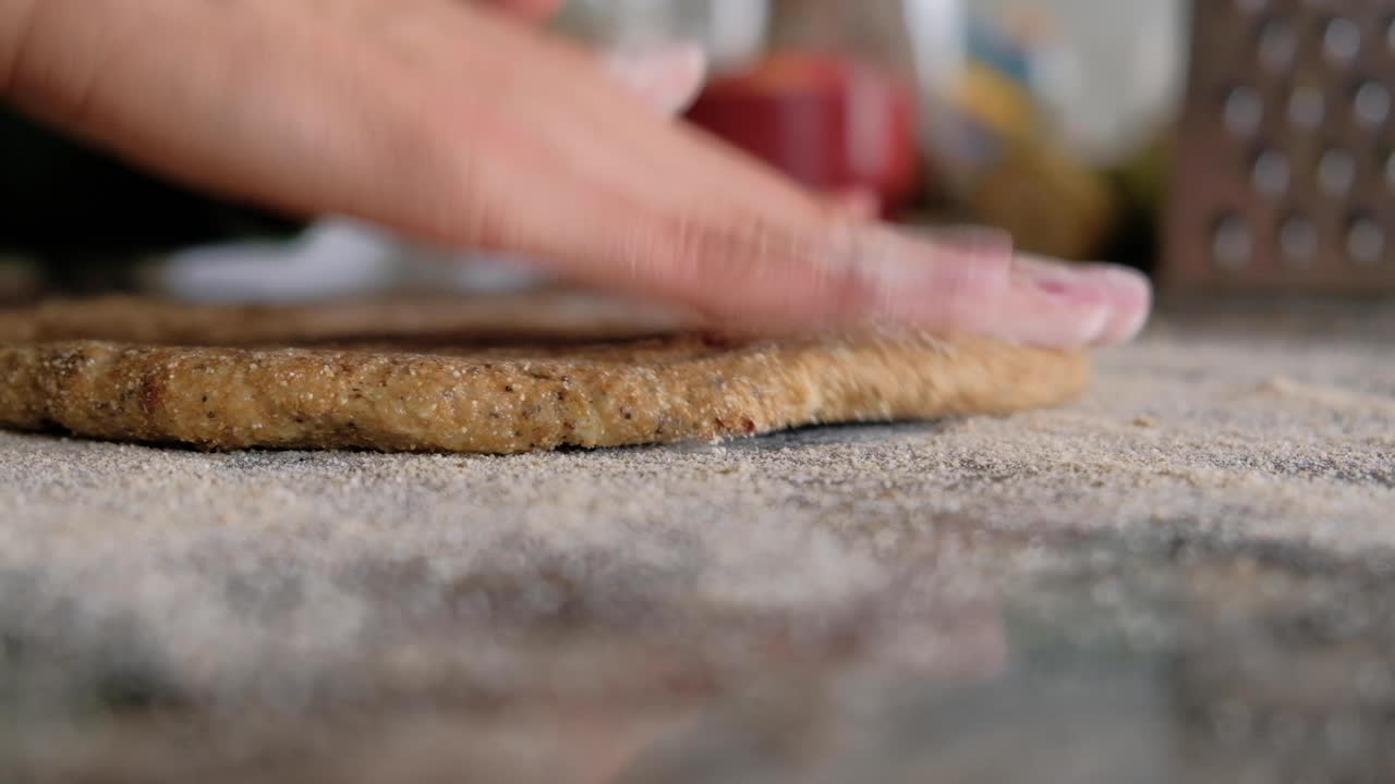 Woman sprinkling flour on countertop and stretching the dough with her fingers