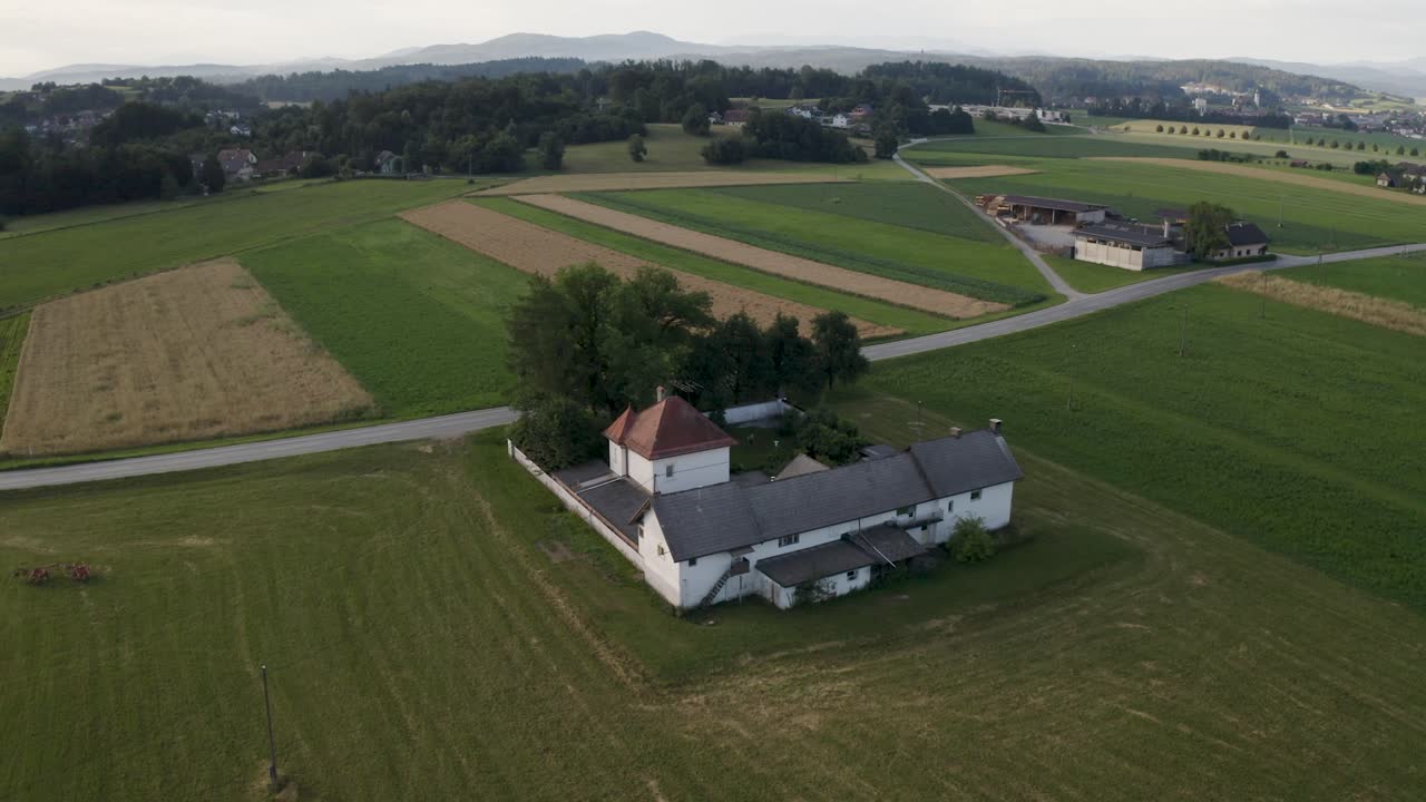 Aerial view of a village in Slovenia. Colorful landscape with village, hills, fields, green grass. Drone