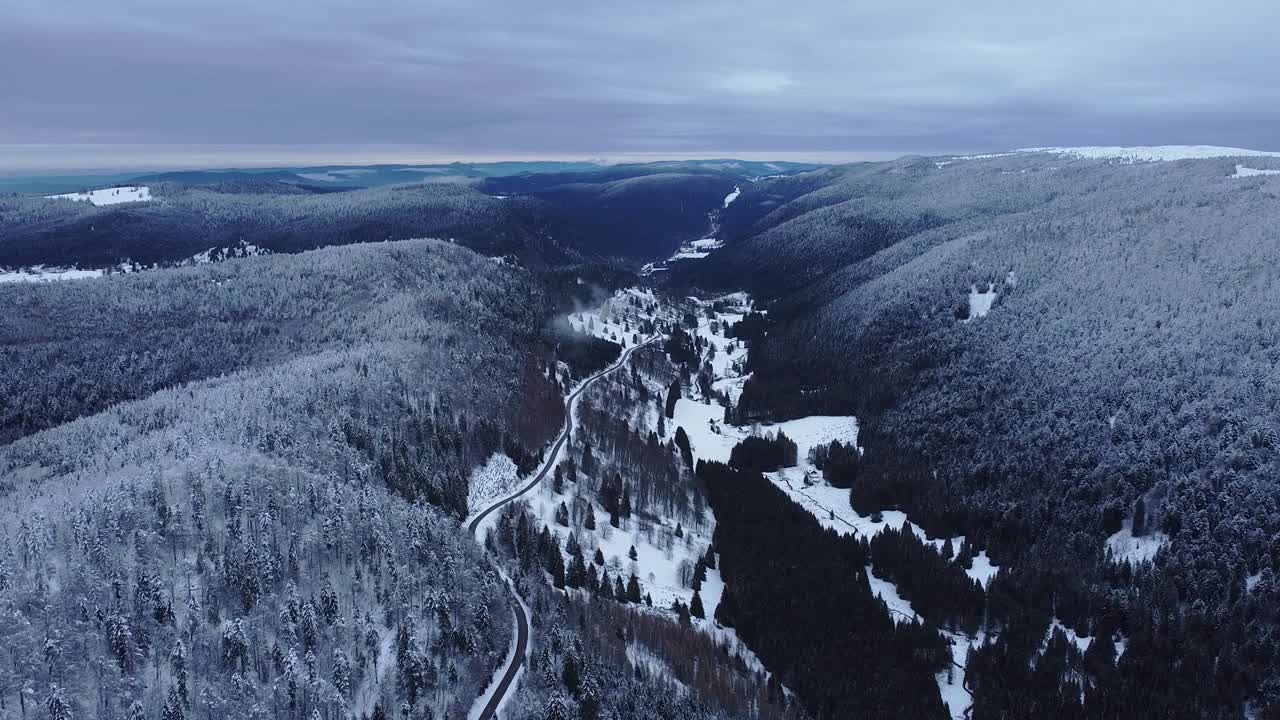 paisaje de carretera de montaña de invierno aéreo cubierto de nieve que muestra un largo horizonte vuelo lento