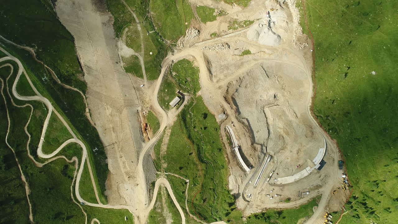 fotografía aérea de un sitio de construcción de una presa en las montañas alpinas