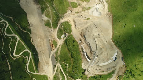 top down aerial drone shot of a dam construction site in the alpine mountains