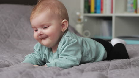 close up ground level view of happy baby girl on blanket lying on her tummy