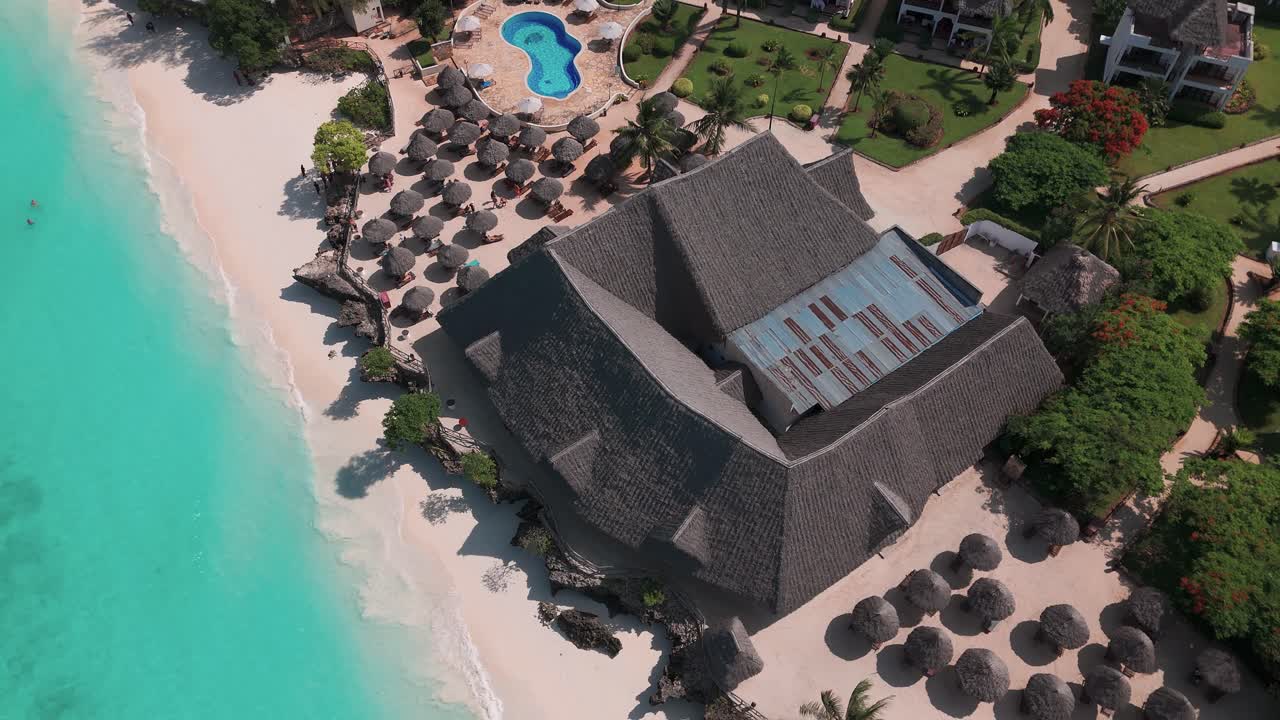 Thatched Roof Sunshades At Sandies Baobab Beach In Zanzibar, Nungwi, Tanzania. Aerial Drone Shot