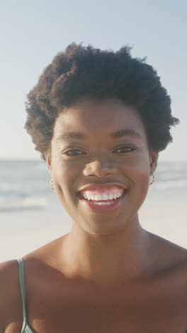 vertical video of portrait of happy african american woman smiling at beach, in slow motion