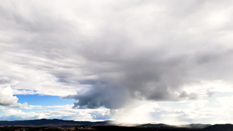 dramatic storm clouds move across a rural australian landscape, with shifting light and shadow over distant hills under a dynamic sky, captured in wide shot