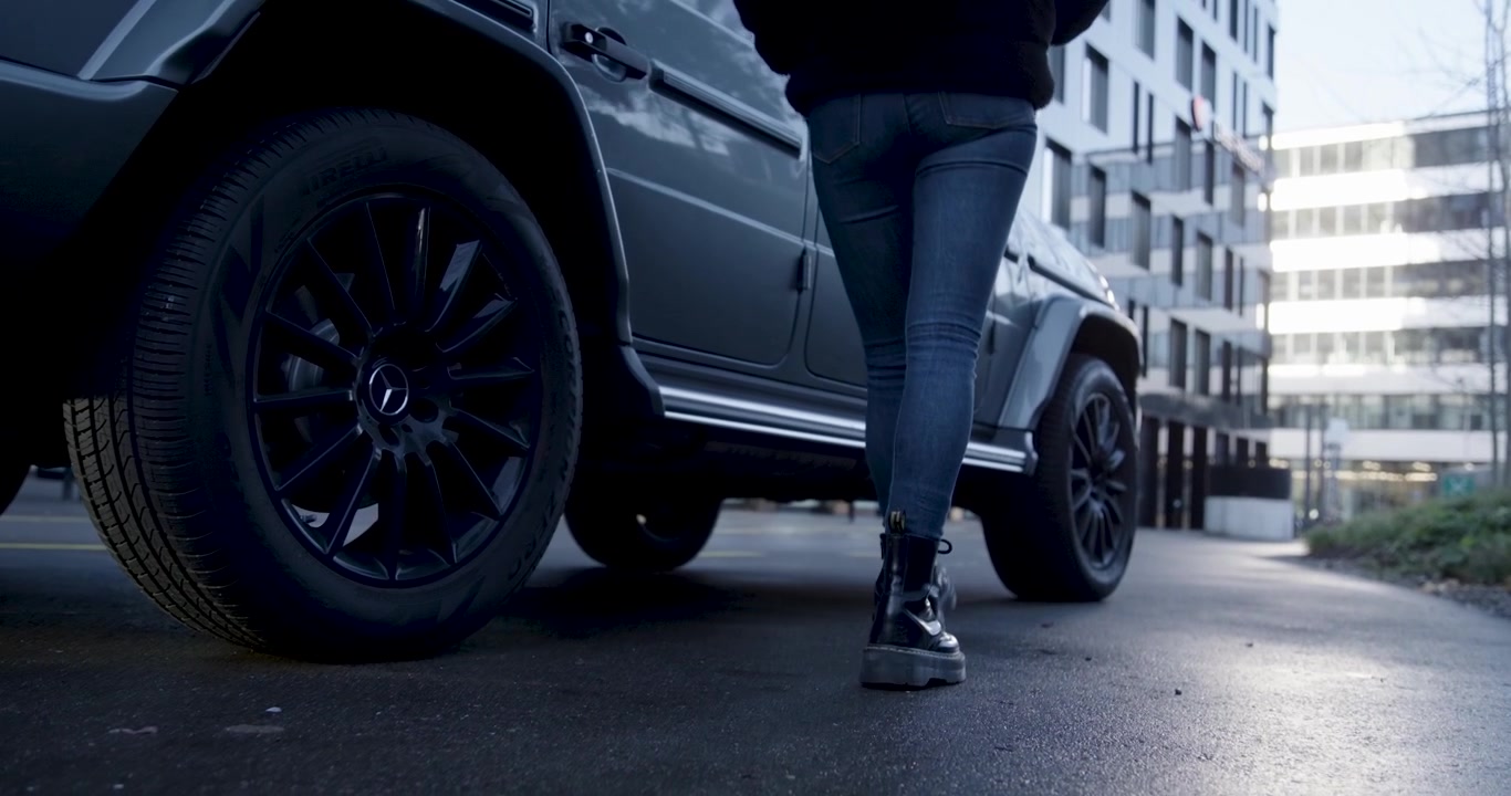 Kvinne i jeans og støvler går til bilen sin