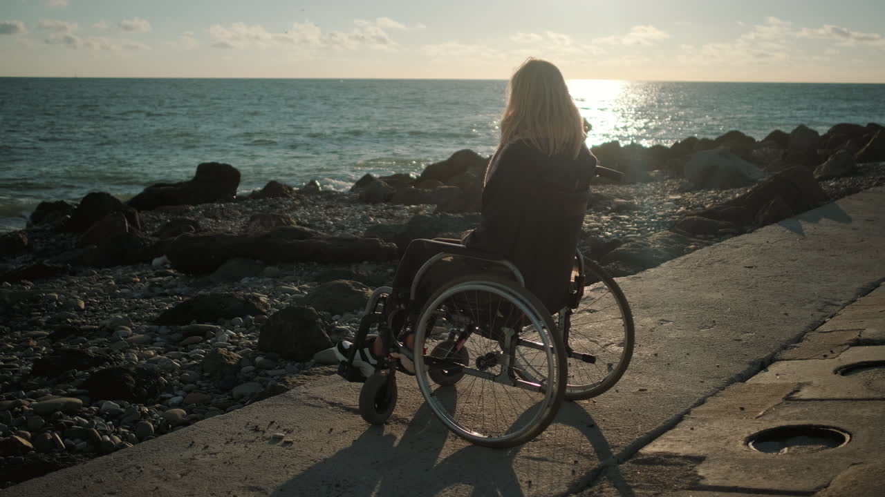 mujer en silla de ruedas en la playa del atardecer