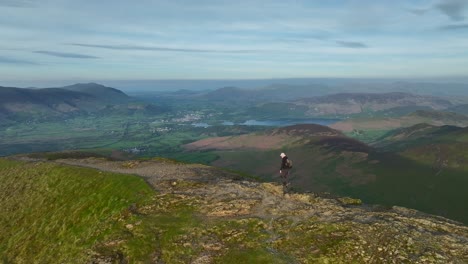 Mountain-walker-trekking-along-rounded-fell-summit-during-golden-hour