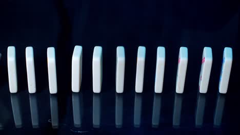 Side-view-of-multi-colored-dominoes-falling-on-black-with-a-reflection