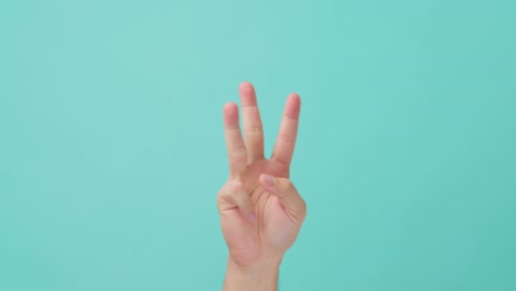 disparo cercano de la mano humana levantando, haciendo un gesto de la mano contando el número uno a cinco con los dedos. el hombre haciendo un semáforo o un signo usando su mano de la palma. visto en una pantalla azul aislada en el fondo.