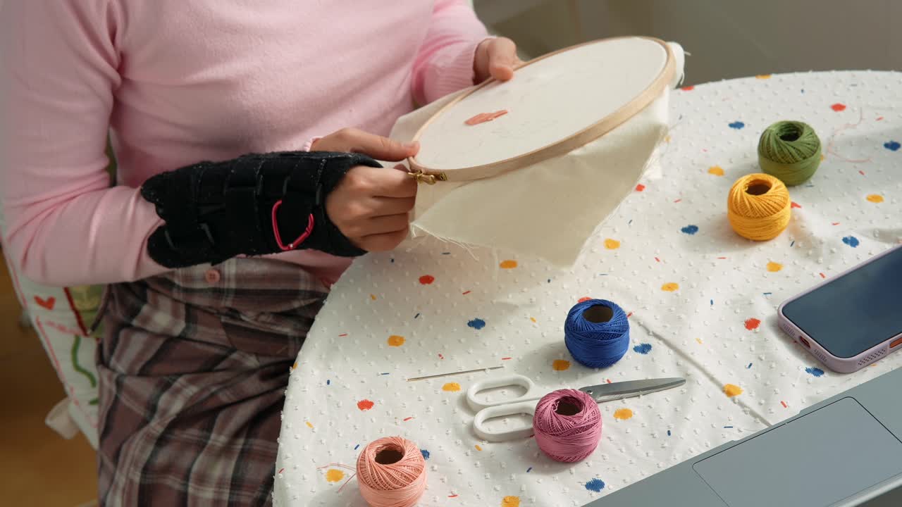 Donna con tutore al polso che si prepara a ricamare un tessuto