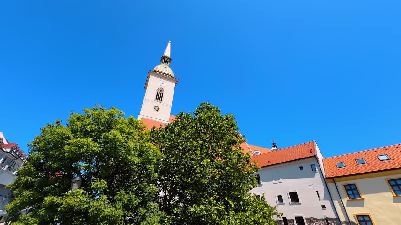Tower of an old church at the backdrop of a blue clear sky. Historical buildings in the old town of Bratislava, Slovakia