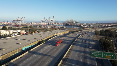 Aerial view of a multi-lane highway leading to a bustling port with numerous cranes and shipping activity