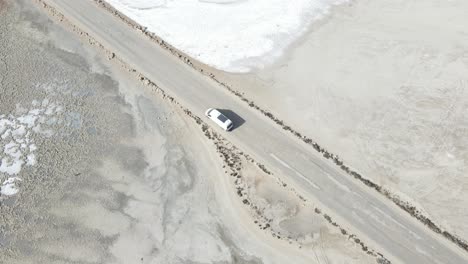 Avión-De-Drones-Sobre-Una-Autocaravana-Blanca-Conduciendo-Por-Una-Carretera-Sobre-El-Lago-Rosado-Macdonnell-En-El-Sur-De-Australia