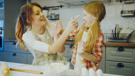 young mother and her lovely daughter having fun with flour in the kitchen while cooking together. indoor