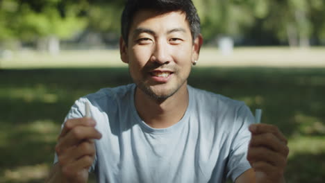 야외에서 두 개의 분필을 보여주는 행복한 아시아 남자의 초상화