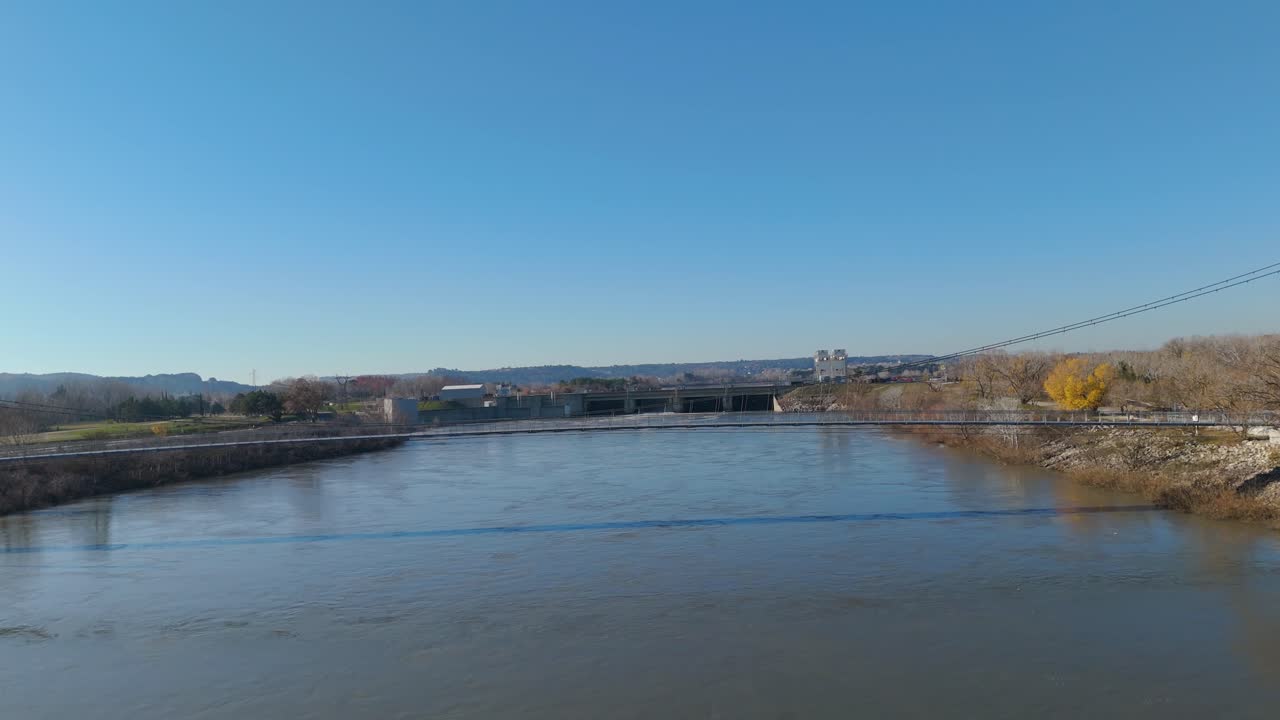Aerial view above the Rhône river with view of the walk bridge and dam, cityscape of sauveterre in the background