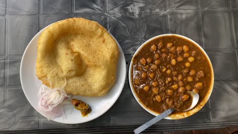 breakfast food from india chole bhature, also known as poori, is a delectable indian meal cooked with all purpose wheat flour and eaten with chickpea chana masala curry mixed pickles and sliced onion