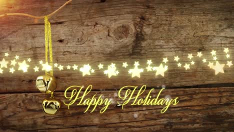Animation-of-text,-happy-holidays,-in-yellow,-over-star-lights-and-christmas-bells-on-wooden-boards