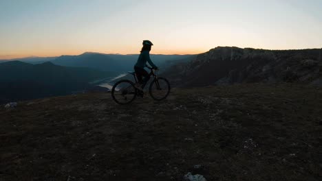 girl riding a bike uphill on a mountain at sunset