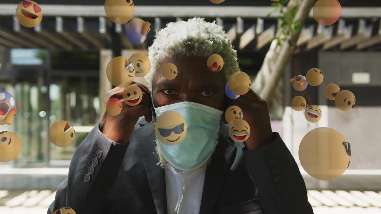 Man adjusting face mask surrounded by floating emoji animations outdoors