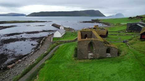 Ruins-of-St-Magnus-Cathedral-and-Faroese-turf-roof-houses,-Kirkjubour