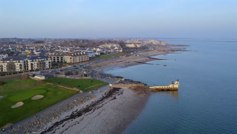 aerial of salthill blackrock diving board and promenade with walkers along the coastline and waves gently hitting the shore, establishing static