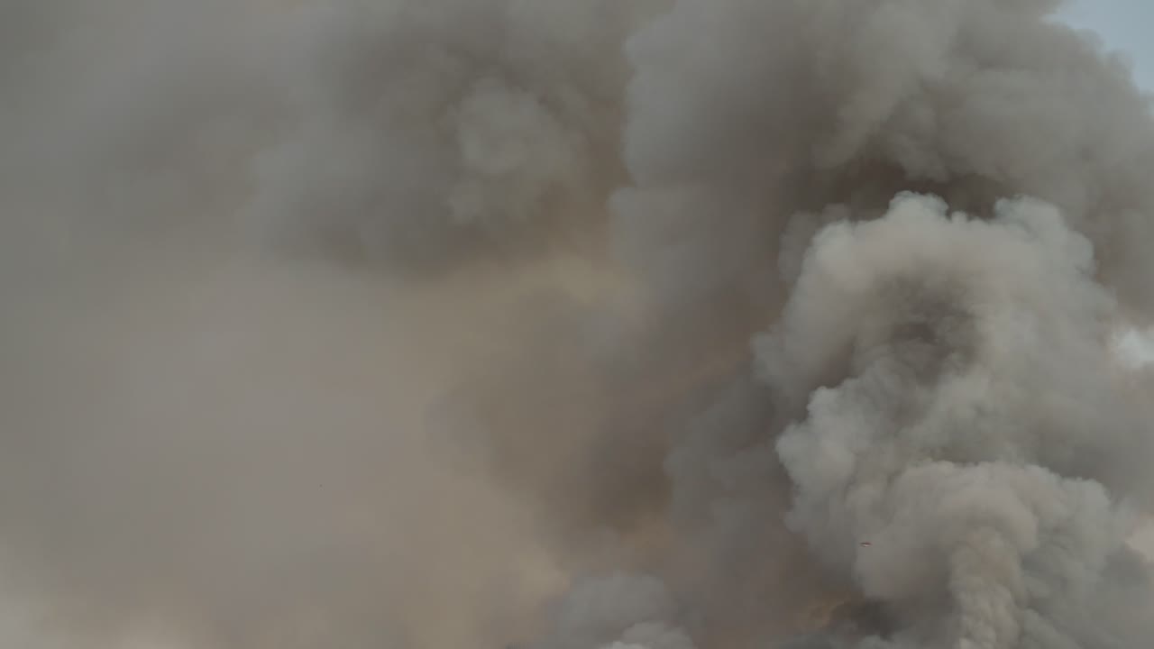 Black smoke clouds and flames rise into the sky.