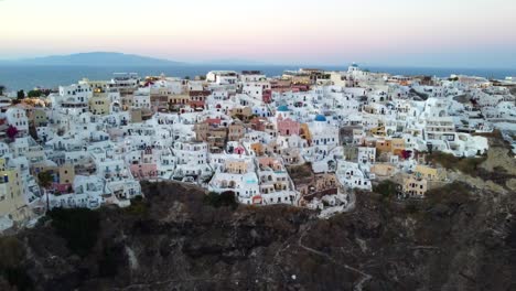 aerial footage of oia, santorini famous white houses and blue domes on the edge of the cliff and blue lagoon