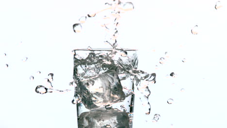 ice cube falling into glass of water