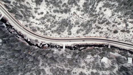 vista aérea de drones de automóviles que circulan por una carretera aislada en un paisaje invernal cubierto de nieve, un bosque de pinos, un valle cerca de kittredge evergreen colorado