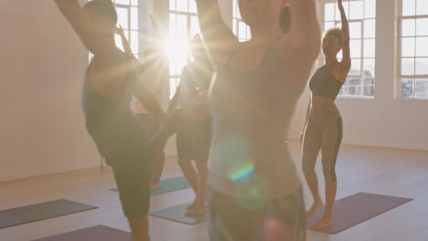 yoga class of young healthy people practicing lord of the dance pose enjoying exercising in fitness studio group meditation with instructor at sunrise