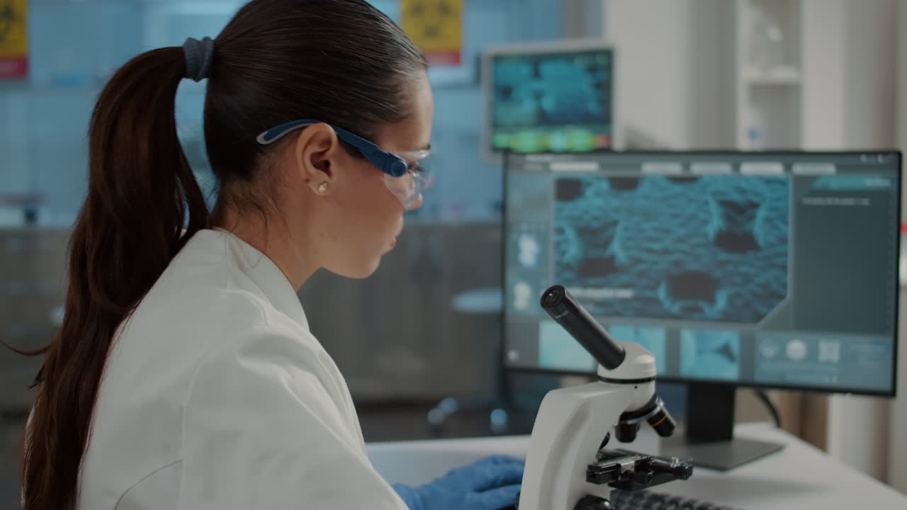 Woman examining dna sample on microscope tray in laboratory