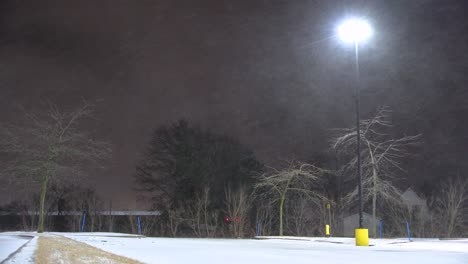 las lluvias de nieve flotando a través del cielo oscuro con una sola lámpara de la calle en saint-jean-sur-richelieu, quebec, canadá
