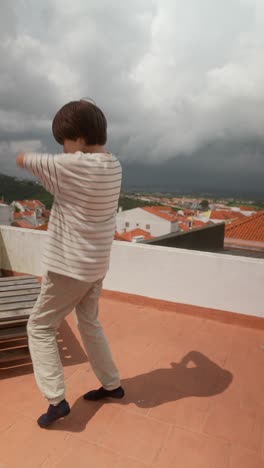 boy dancing on a rooftop with a city view