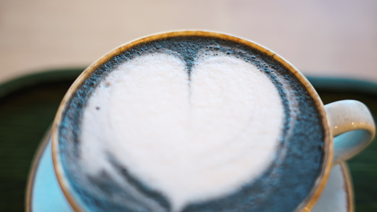 Blue matcha latte with heart shape foam in a ceramic mug