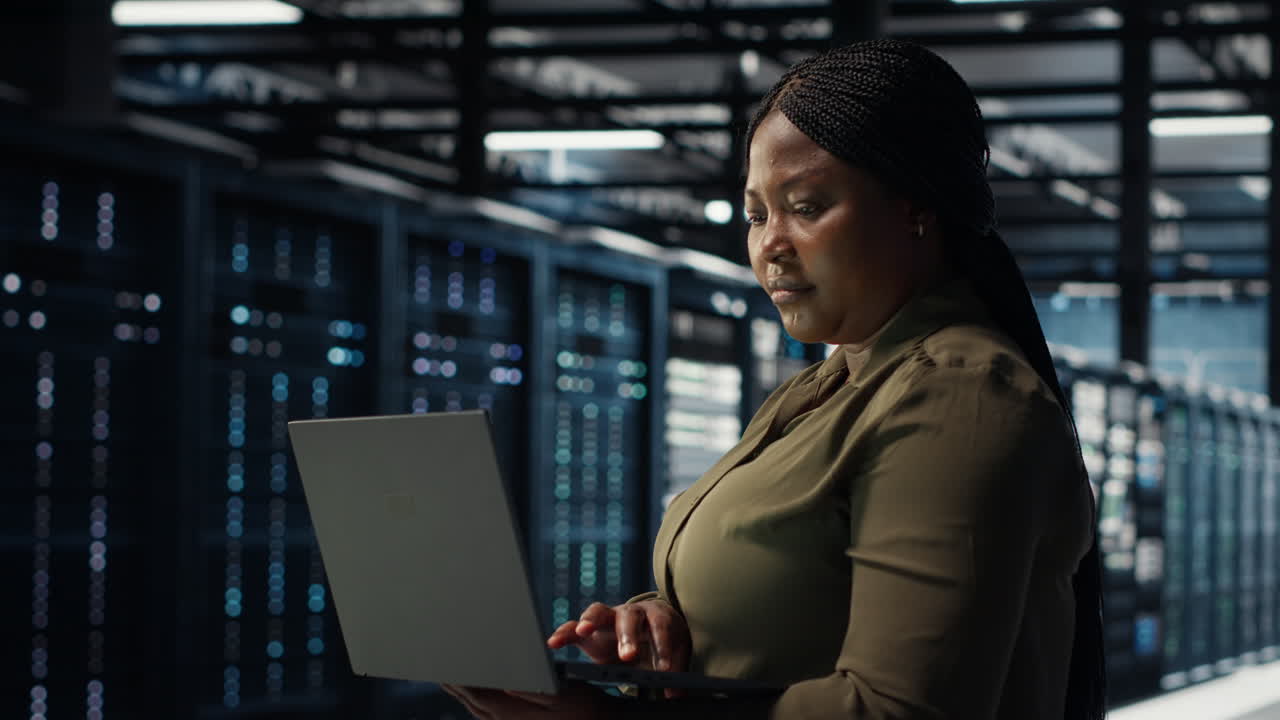 Software developer in data center using laptop to upgrade systems