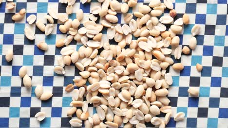 scattered shelled peanuts on checkered tablecloth