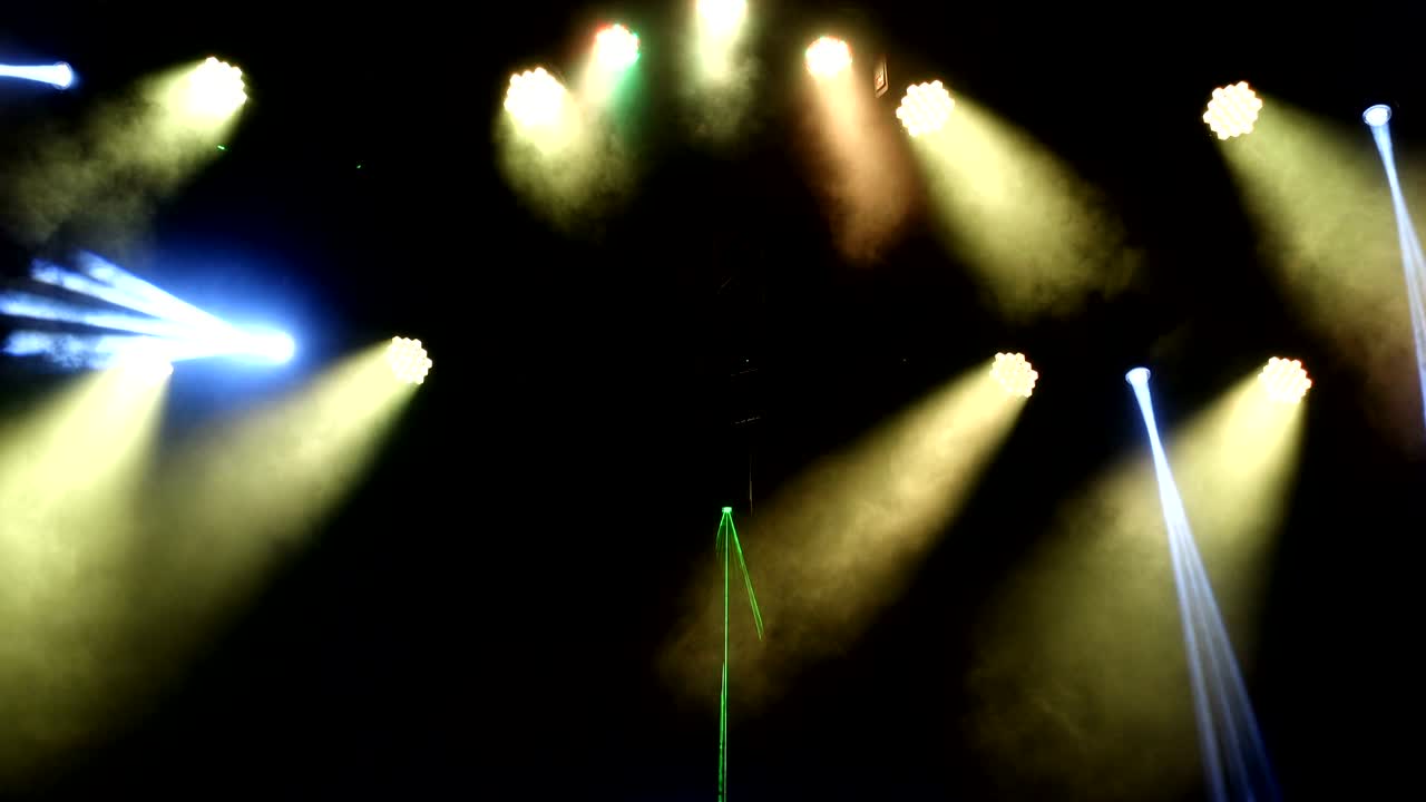 brillantes reflectores de concierto parpadeantes láseres y humo en el fondo de la escena